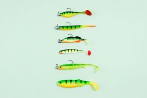 A selection of bright fishing lures laid out on a pastel green surface.